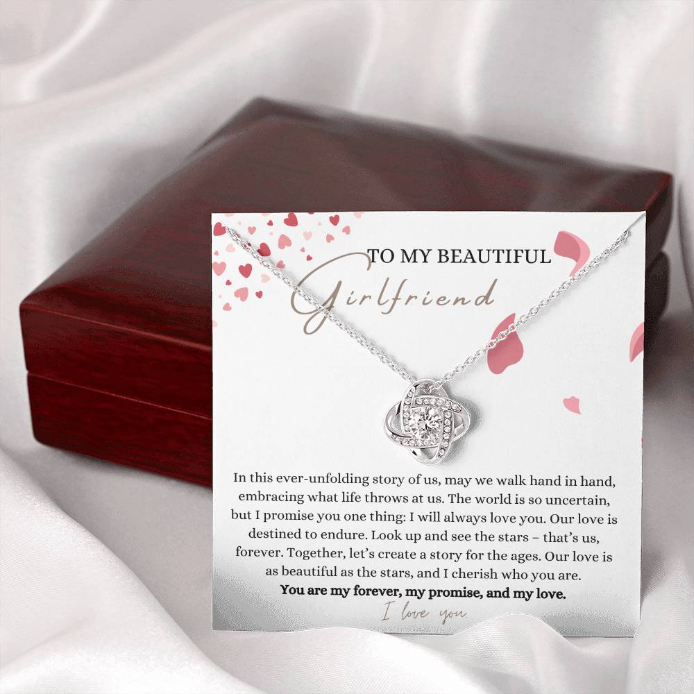 A white gold finish necklace gift, with a knot pendant embellished with premium cubic zirconia crystals, and a message card to my beautiful girlfriend, next to a mahogany Jewelry box.