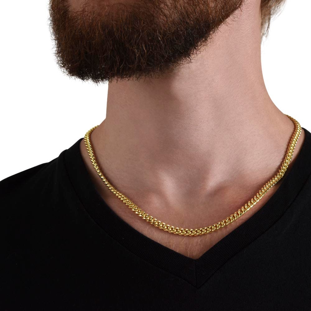 A man wearing a Cuban chain necklace with a yellow gold finish.