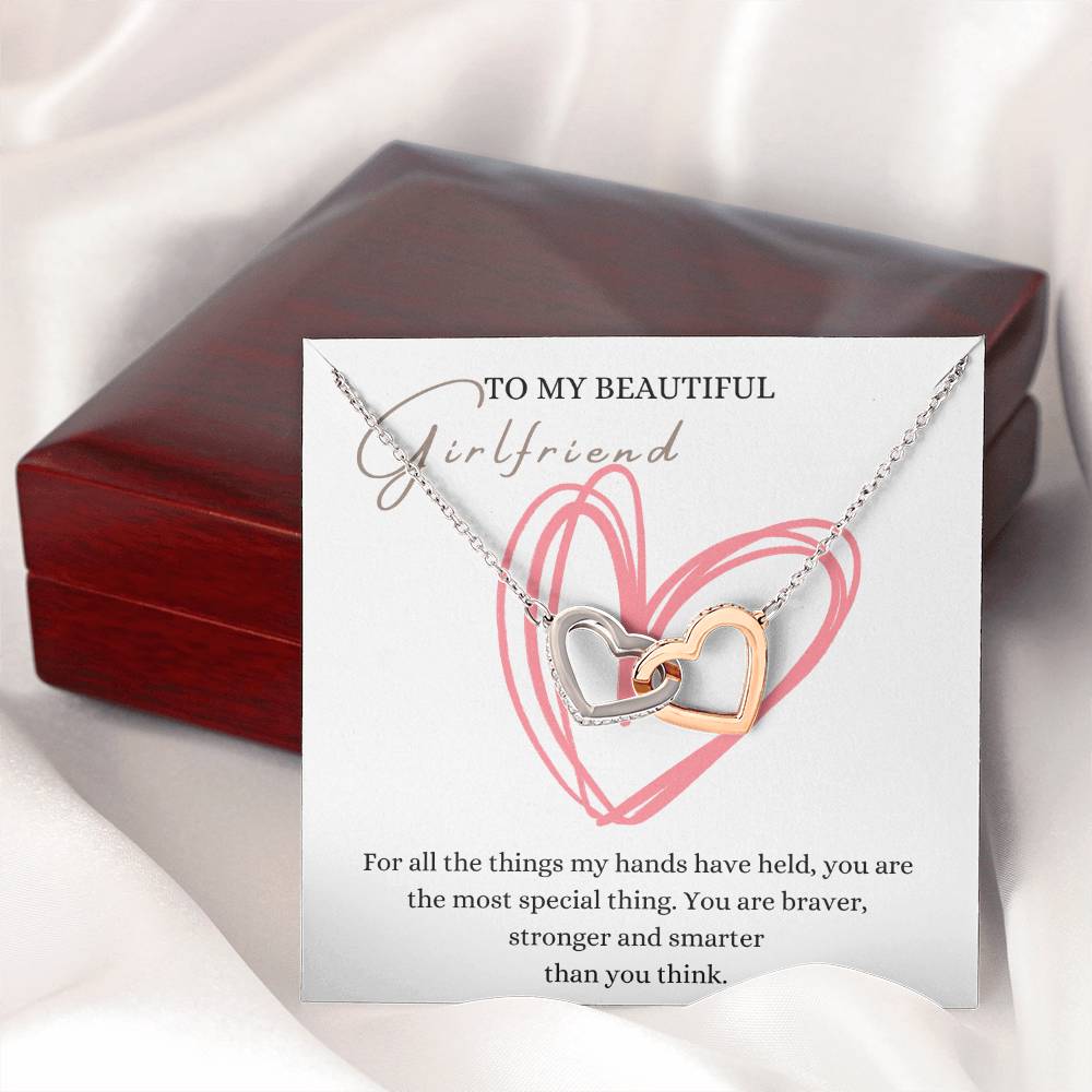 A necklace gift with ribbon shaped pendant with cubic zirconia crystals and white gold finish, with a message card to my beautiful girlfriend, next to a mahogany Jewelry box.